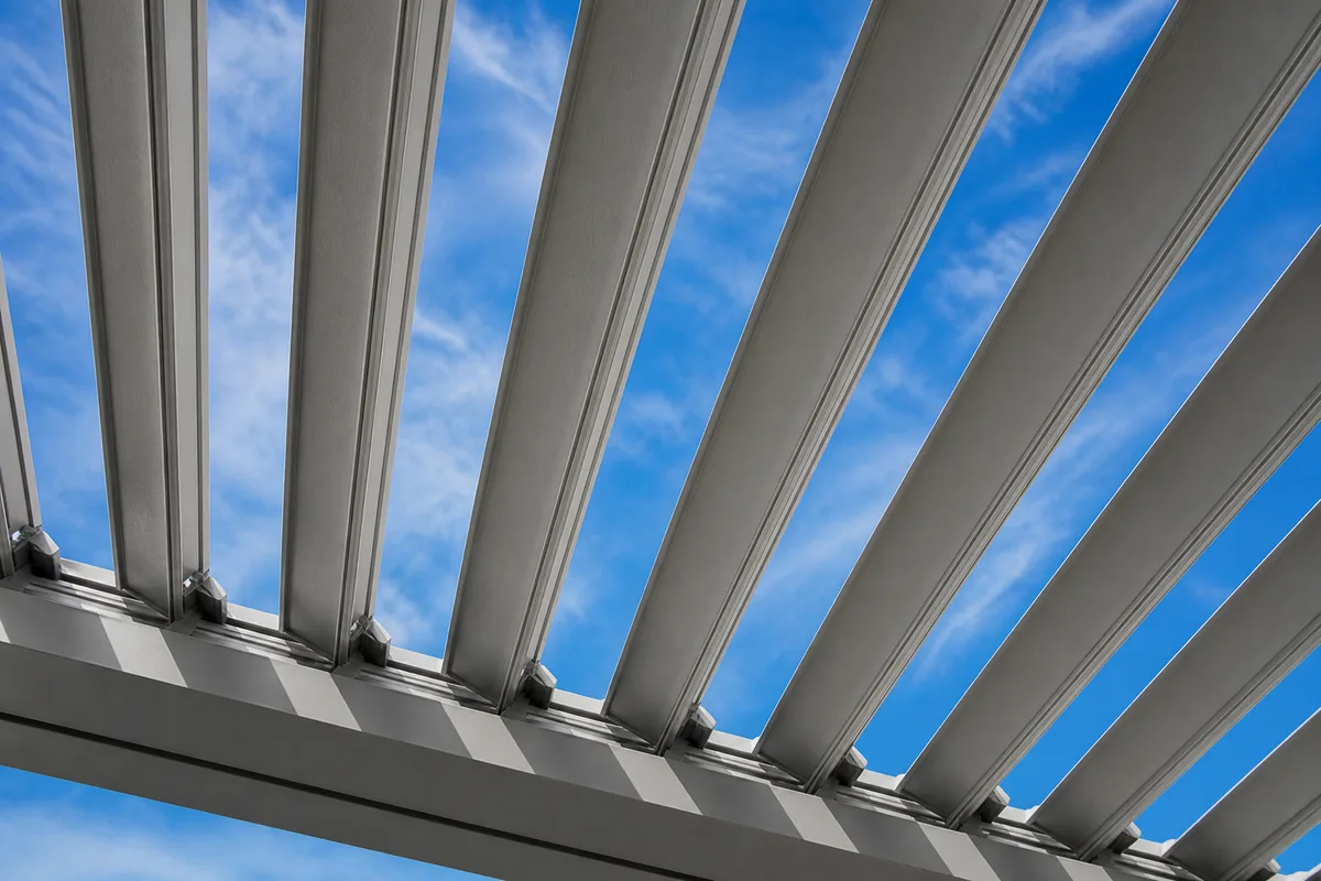 Pergola bioclimatique en aluminium sur une terrasse, lames entrouvertes en fin de journée